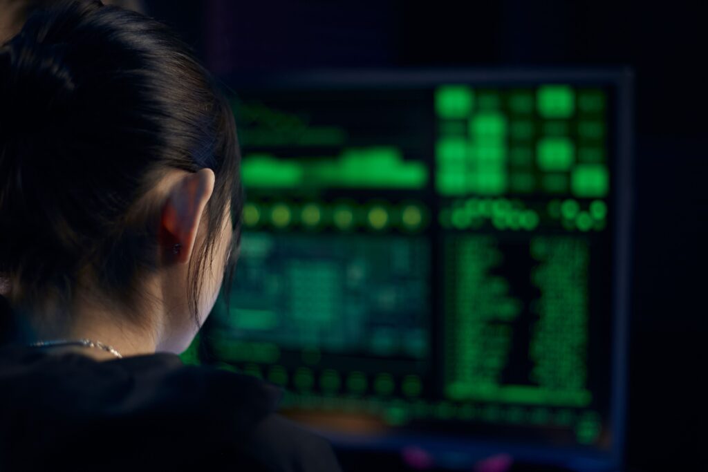 A woman focuses on data displayed on a computer screen in a dark room.